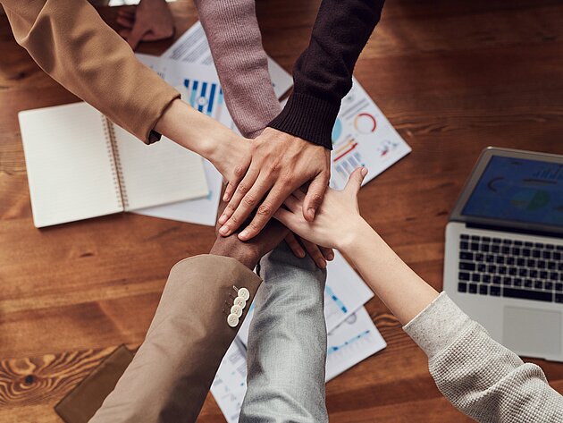 Mehrere Personen stapeln ihre Hände übereinander