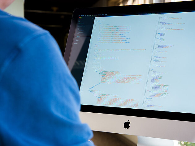 Bildschirm mit mehreren angezeigten Daten wird von Person in blauen T-Shirt benutzt